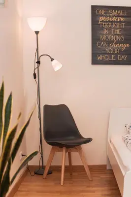 a black chair sitting next to a lamp in a room at Agnės svečių namai in Kaunas