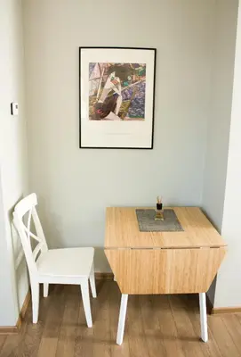 a table and a chair in a room with a picture on the wall at Owl Apartments in Kaunas