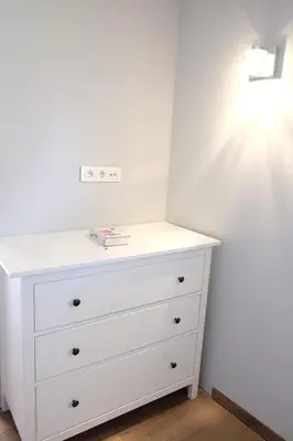 a white dresser in a room with a white wall at Owl Apartments in Kaunas