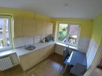 a kitchen with a sink and a table and two windows at Kambarių nuoma Kačerginės kurorte in Kačerginė