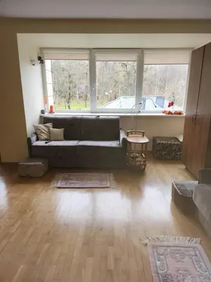 a living room with a couch and a large window at Ramresort Apartment in Birštonas