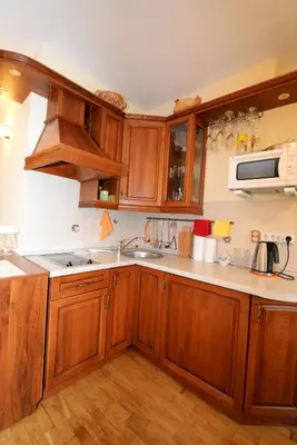 a kitchen with wooden cabinets and a sink at Ramresort Apartment in Birštonas