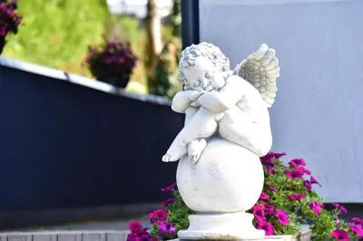a white angel statue sitting on top of flowers at MS Resort in Nemėžis