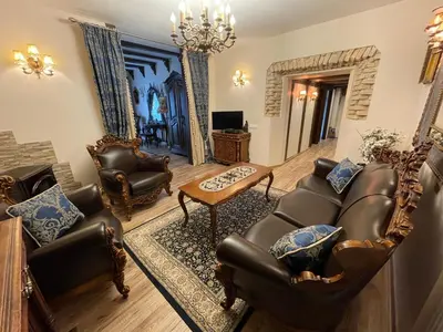 a living room with leather furniture and a chandelier at Grand Duke Apartments in Vilnius