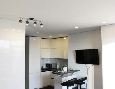 a kitchen with white cabinets and a flat screen tv at New Studio In Oslo Namai in Vilnius
