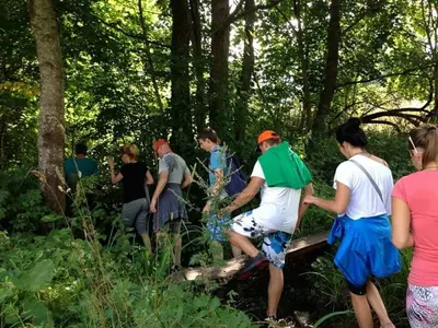 a group of people standing around in the woods at Namelis šalia vynuogyno in Būdziliai