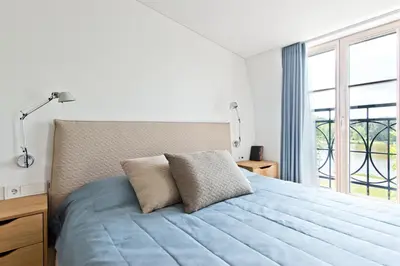 a bedroom with a blue bed with a window at Aura apartamentai in Druskininkai
