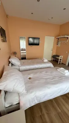 three beds in a room with a tv on the wall at Apartamentai KAVA in Zarasai
