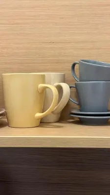 three coffee cups sitting on a wooden shelf at Apartamentai KAVA in Zarasai