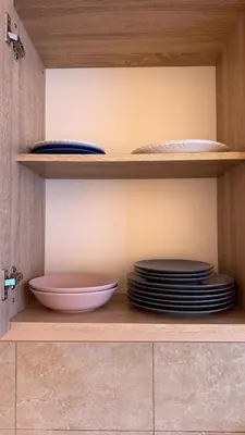 a shelf with plates and bowls in a cabinet at Apartamentai KAVA in Zarasai