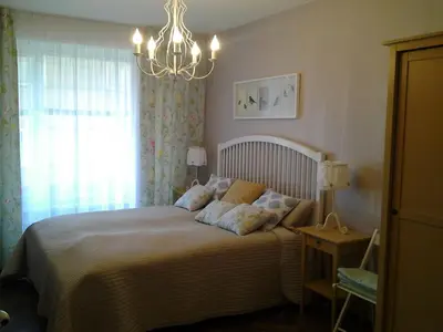 a bedroom with a bed with a chandelier and a window at Luxury Apartment in Druskininkai