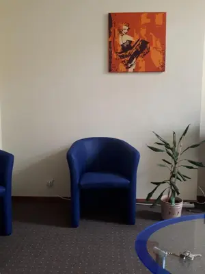 a blue chair in a waiting room with a plant at Valentina's Rooms in Vilnius
