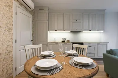 a kitchen with a wooden table with plates and wine glasses at SoulHouse apartments in Druskininkai