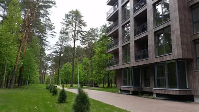 a building in a park with trees and a sidewalk at SoulHouse apartments in Druskininkai