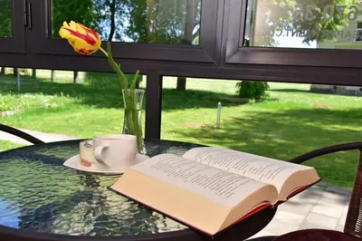 an open book on a table with a cup and a flower at Oksanos apartamentai Druskininkuose atskiras įėjimas 1 aukštas in Druskininkai
