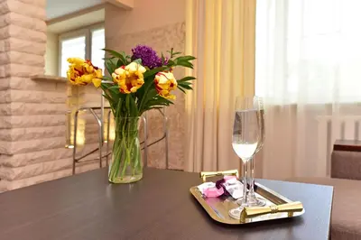 a vase of flowers and a glass of wine on a table at Oksanos apartamentai Druskininkuose atskiras įėjimas 1 aukštas in Druskininkai