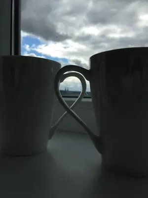 two coffee cups sitting on a window sill at Angel's Dream Apartment in Anykščiai