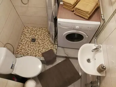 a bathroom with a toilet and a sink and a washing machine at Draugystės Apartment in Šiauliai