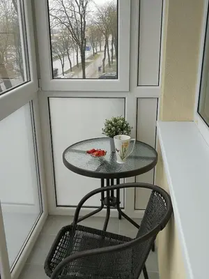 a small table and a chair in a room with windows at Draugystės Apartment in Šiauliai