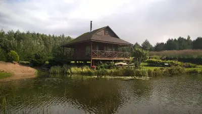 a large building sitting on the side of a lake at Mikalojiškis in Inturkė