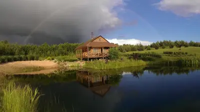 a house on the shore of a lake with a rainbow at Mikalojiškis in Inturkė