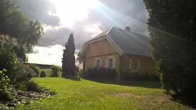 a house in a yard with the sun shining at Kačiūniškis in Kaciūniškiai