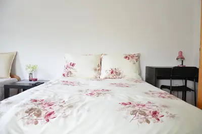 a bed with a white blanket with pink flowers on it at Apartments with outdoor SPA jacuzzi and sauna in Vilnius