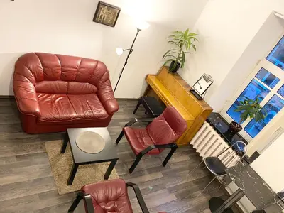 a living room with a leather chair and a piano at Centro apartment near Gedimas Avenue in Vilnius