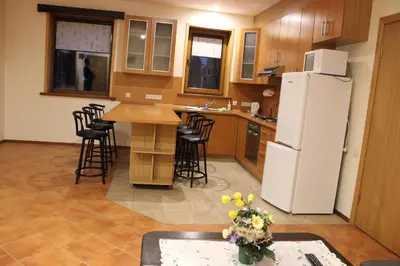 a kitchen with a white refrigerator and some chairs at Vidų Guest House in Utena