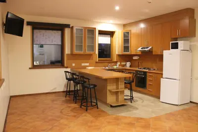 a kitchen with wooden cabinets and a white refrigerator at Vidų Guest House in Utena