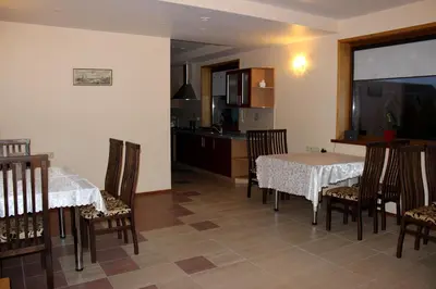 a dining room with two tables and chairs and a kitchen at Vidų Guest House in Utena
