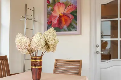 a vase of flowers on a table with a painting at Vila Liepa in Birštonas
