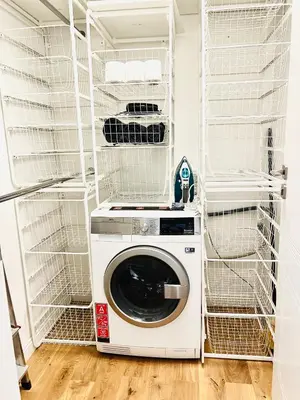a washing machine in a laundry room with white shelving at Tomy Old Town Apartments in Vilnius