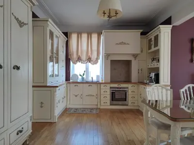 a large kitchen with white cabinets and a table at Broadway apartament in Šiauliai