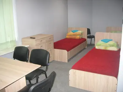 a classroom with two beds and a desk and chairs at Hostelis Laurita in Kaunas