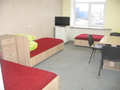 a room with two beds and a desk and a television at Hostelis Laurita in Kaunas