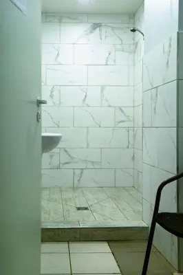 a bathroom with a shower with white tiles at Hostelis Laurita in Kaunas