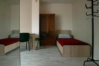 a room with two beds and a desk and a chair at Hostelis Laurita in Kaunas