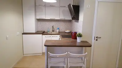 a kitchen with white cabinets and a counter with two stools at Igo Apartment Townhall in Vilnius