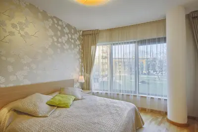 a bedroom with a bed and a large window at Apartamentai Liuks in Druskininkai
