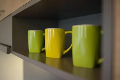 three green coffee mugs sitting on a shelf at Apartamentai Liuks in Druskininkai