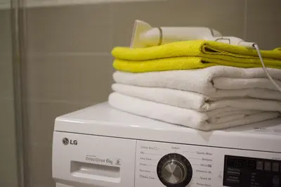 a stack of towels sitting on top of a washing machine at Apartamentai Liuks in Druskininkai
