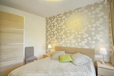 a bedroom with a bed with a flower patterned wall at Apartamentai Liuks in Druskininkai