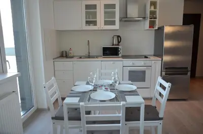 a kitchen with a table with chairs and a refrigerator at Apartments Ozo Park in Vilnius