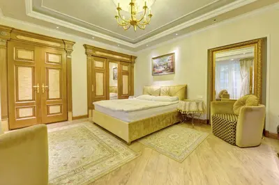 a bedroom with a bed and two chairs and a chandelier at Luxury Pilies Avenue Apartment in Vilnius