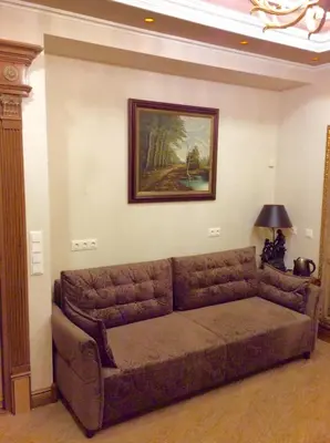 a couch in a living room with a painting on the wall at Luxury Pilies Avenue Apartment in Vilnius