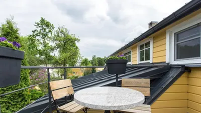 a balcony with a table and chairs on a roof at Inga Vacation House in Druskininkai