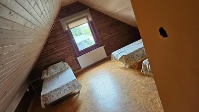 an attic room with two beds and a window at Domeikavos vila in Ražiai