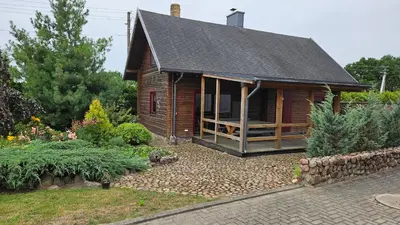 a small wooden house with a garden in front of it at Domeikavos vila in Ražiai