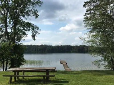 a picnic table next to a lake with a dock at Kaimo Turizmo Sodyba Šniūrai in Mindūnai